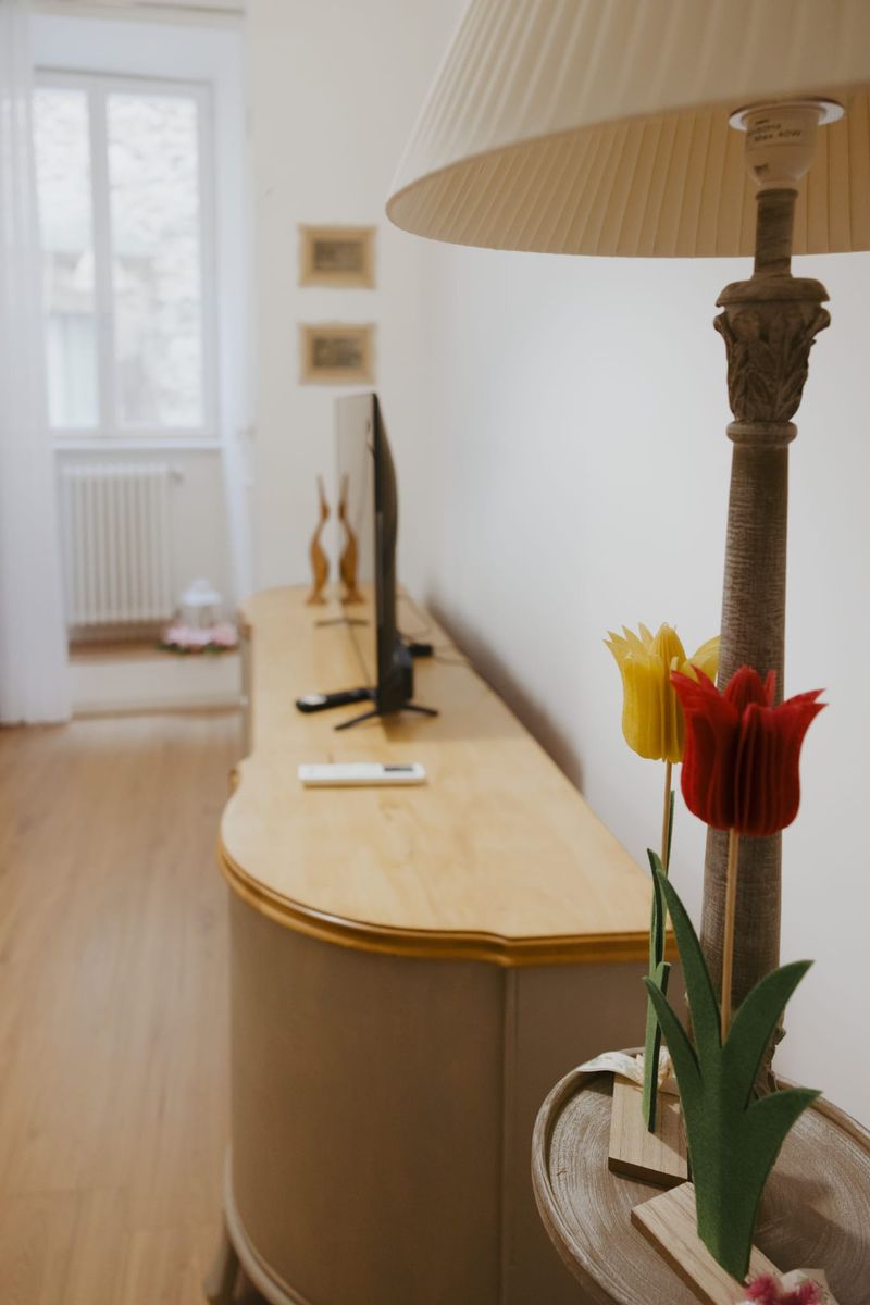 Credenza restaurata del soggiorno con lampada a colonna e tulipani di feltro in primo piano